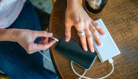 Close-up of Woman's hands plugging a mobile phone into apower bank  in a bar