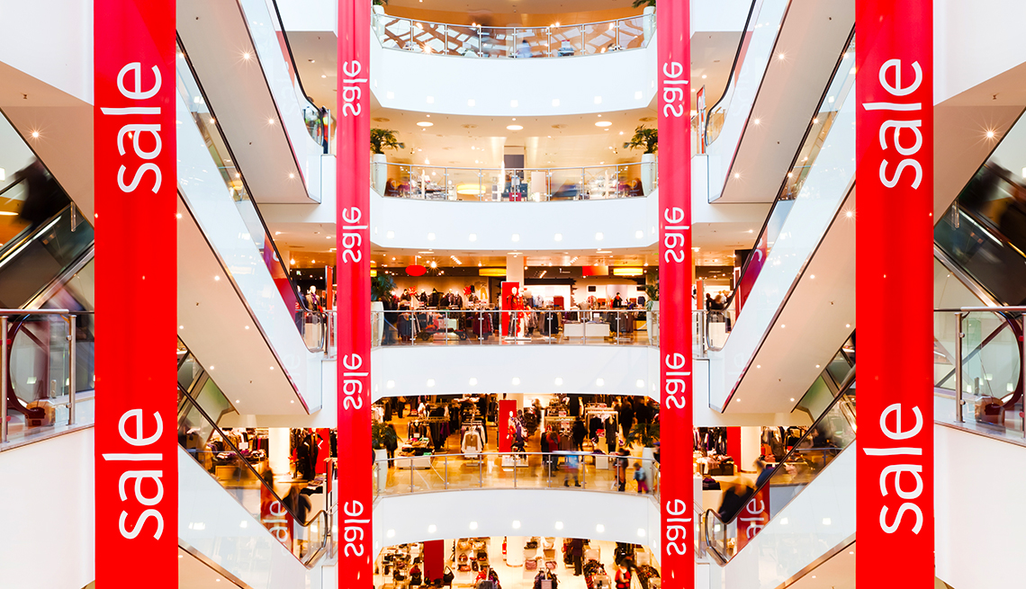 wide view of a big shopping mall decorated with red "Sale" banners hanging down from top to bottom of the interior space