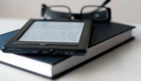 E-Reader and book with reading glasses.