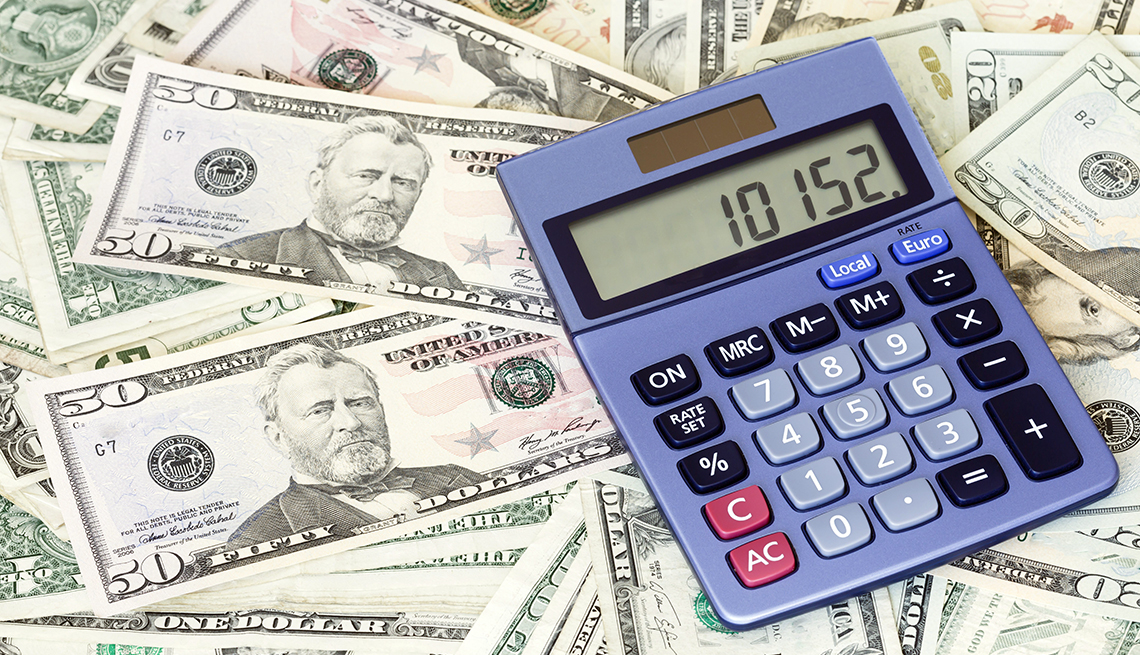 A blue calculator sits on a background of U.S. currency of varying dollar amounts.