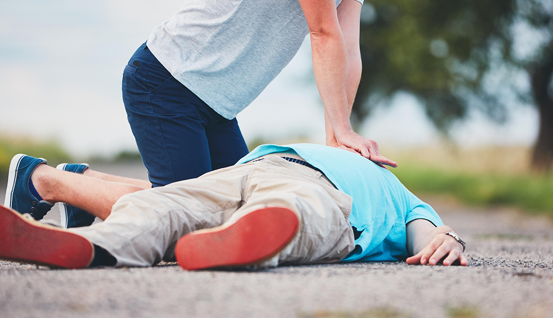 Hombre administra reanimación cardiopulmonar a otro hombre en el suelo