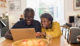 Mature couple smiling and looking at a laptop together