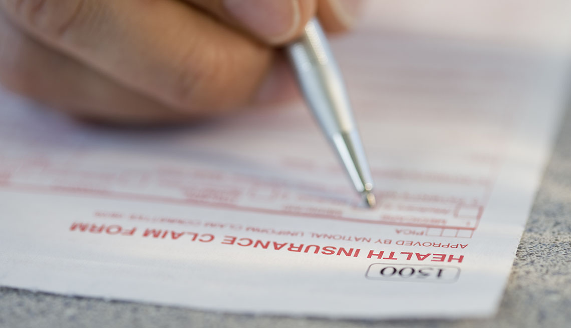 Persona llena un documento de una aseguradora médica con un bolígrafo