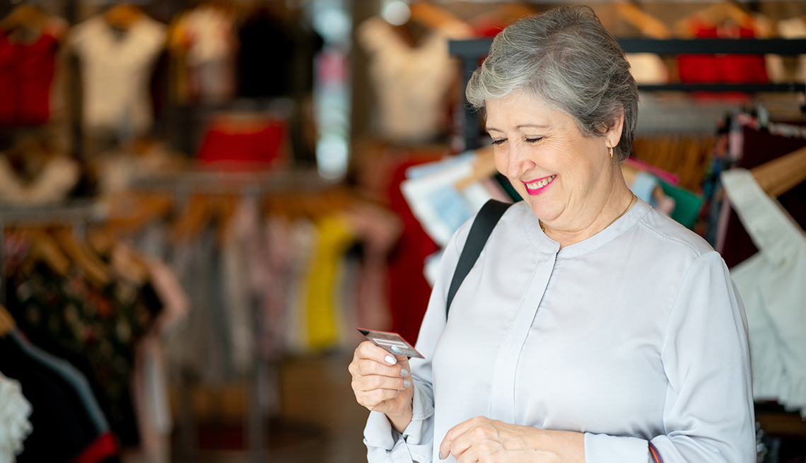 smiling woman shopping in a clothing store looking at her credit card