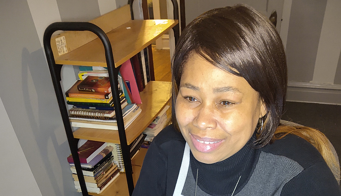 African American woman wearing black and grey sweater with a bookshelf in the background